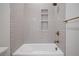 Bright bathroom shower-tub combination with white subway tile, niche shelving and gold fixtures at 1601 S Columbine St, Denver, CO 80210
