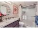 Bathroom featuring granite counters, a vanity sink, round mirror and shower with glass doors at 4505 S Yosemite St # 102, Denver, CO 80237