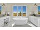 Luxurious bathroom with a freestanding tub, dual vanities, and picturesque outdoor views at 7572 Kelty Trl, Franktown, CO 80116