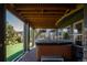 Covered outdoor hot tub on a brick patio with wooden beams overhead and a view of the landscaped backyard and surrounding houses at 6787 Serena Ave, Castle Pines, CO 80108