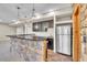 Basement bar with a stone facade, cabinets, shelving, pendant lighting, and a stainless steel refrigerator at 9754 W Ontario Pl, Littleton, CO 80128