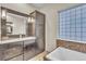 Bathroom with a modern vanity, tiled floors, and a decorative glass-block window above the soaking tub at 9754 W Ontario Pl, Littleton, CO 80128