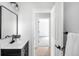 Bright bathroom featuring a black vanity, rectangular mirror, and doorway to another room at 3065 S Eudora St, Denver, CO 80222