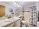 Bright bathroom with a vanity sink, tile floor, and adjacent shower with curtain at 3803 Dyanna Dr, Thornton, CO 80241