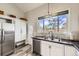 Well-lit kitchen featuring a stainless steel dishwasher and sink, and updated cabinetry at 3803 Dyanna Dr, Thornton, CO 80241