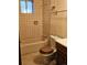 Compact bathroom featuring tiled walls, a standard tub, and a matching toilet, offering essential amenities at 3841 Myers Gulch Rd, Kittredge, CO 80457