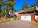 This exterior elevation showcases a two-story home, driveway, and an attached garage with a wooden deck above at 3841 Myers Gulch Rd, Kittredge, CO 80457
