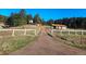 Scenic shot of the property featuring a long driveway leading to the home and a barn, framed by a white fence at 3841 Myers Gulch Rd, Kittredge, CO 80457