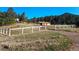 Scenic view of a property with a barn and a home in the distance, surrounded by lush trees and a white fence at 3841 Myers Gulch Rd, Kittredge, CO 80457
