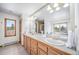 Bright bathroom with dual sinks, wooden cabinets, and a scenic view from the window at 2049 Silverheels Dr, Larkspur, CO 80118