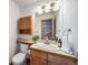 Charming bathroom with wooden cabinets and a tiled countertop with a view of a brick wall at 2049 Silverheels Dr, Larkspur, CO 80118