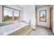 Bright bathroom with a large tub, a shower, and a view of the trees outside at 2049 Silverheels Dr, Larkspur, CO 80118