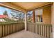 Covered balcony featuring wooden railings and beams, offering a view of mature trees at 3035 Oneal Pkwy # 20V, Boulder, CO 80301