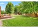 Lush backyard with expansive green space, mature trees, and inviting deck, perfect for relaxation and recreation at 7703 S Grape Ct, Centennial, CO 80122