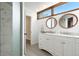 Bright bathroom with double vanity, wood-framed mirrors, and modern tile flooring at 7703 S Grape Ct, Centennial, CO 80122