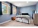 Comfortable bedroom showcasing three windows, light blue walls, and carpeted flooring at 7703 S Grape Ct, Centennial, CO 80122