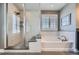 A bright bathroom boasts a walk-in shower, soaking tub, and large window with shutters, creating a spa-like retreat at 10178 Nadine Ave, Parker, CO 80134