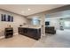 Basement wet bar area with dark cabinetry, stone countertops, and adjacent entertainment space at 10178 Nadine Ave, Parker, CO 80134