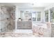 Bright bathroom featuring marble accents, a glass shower, and a soaking tub with natural light from the windows at 3901 S Dexter St, Cherry Hills Village, CO 80113