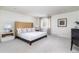 A spacious bedroom with neutral tones, plush carpeting, a large upholstered headboard, and a picture window at 3901 S Dexter St, Cherry Hills Village, CO 80113