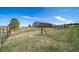 Barn with corral and surrounding green pasture under a blue sky at 12973 Mesa View Rd, Larkspur, CO 80118