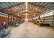 Spacious barn interior featuring high ceilings, wood beams, metal walls, and a dirt floor with tractors at 12973 Mesa View Rd, Larkspur, CO 80118