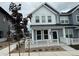 Charming gray townhome featuring a white fence, a well-maintained yard, and a welcoming entrance at 14556 W 91St Ave # D, Arvada, CO 80005