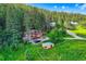 Aerial view of log cabin nestled among lush greenery with additional buildings at 8758 S Murphy Gulch Rd, Littleton, CO 80127