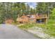 Exterior view of log cabin with detached living space and spacious deck surrounded by lush greenery at 8758 S Murphy Gulch Rd, Littleton, CO 80127