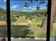 View of the landscape from inside the home, showcasing lush greenery and distant houses at 8758 S Murphy Gulch Rd, Littleton, CO 80127