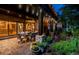 Relaxing outdoor patio with ample seating, manicured gardens, and a view of the home's kitchen at twilight at 12570 W 60Th Ave, Arvada, CO 80004