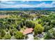 Aerial view of a home with red tile roof surrounded by trees and overlooking a pond at 12570 W 60Th Ave, Arvada, CO 80004