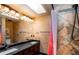 Bathroom boasting double sinks, a large mirror, custom lighting, and a shower with decorative tile and a skylight at 12570 W 60Th Ave, Arvada, CO 80004
