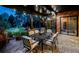 Cozy outdoor patio with a dining table, chairs, string lights, and a view of the lush, landscaped backyard at dusk at 12570 W 60Th Ave, Arvada, CO 80004