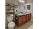 A full bathroom with a double vanity, dark wood cabinets, granite countertops and a separate toilet at 1425 Blue Sky Cir # 15-107, Erie, CO 80516