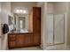 This bathroom features a wood vanity, granite countertop, modern sink and walk in shower at 1425 Blue Sky Cir # 15-107, Erie, CO 80516