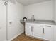 Clean laundry room offers gray counter, white cabinets, modern faucet, and wood-look floors at 8481 Clarkson St, Denver, CO 80229