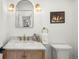 Stylish powder room with gold fixtures, custom wood cabinet, and an arched mirror at 5944 E Irwin Pl, Centennial, CO 80112