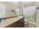 Bright bathroom featuring a spacious vanity, decorative wall art, and a shower with a floral curtain at 17102 W 85Th Pl, Arvada, CO 80007