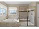 Bright bathroom featuring a soaking tub, a glass shower, and a view to the outside at 17102 W 85Th Pl, Arvada, CO 80007