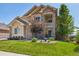 Charming two-story home featuring a stone facade, manicured lawn, and lush landscaping at 17102 W 85Th Pl, Arvada, CO 80007