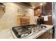 Gas stove and granite countertops with a stainless steel pot filler and a decorative backsplash at 17102 W 85Th Pl, Arvada, CO 80007