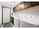 Clean laundry room features white washer and dryer, overhead cabinets, and a white quartz countertop at 6656 S Oak Cir, Littleton, CO 80127