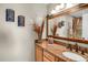 The bathroom has a wooden framed mirror, decorative sconces, and a granite countertop at 1465 Arabian Trl, Elizabeth, CO 80107