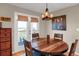 Cozy dining area with a round wooden table, seating for four, a modern chandelier, and views of the outdoors at 1465 Arabian Trl, Elizabeth, CO 80107