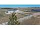 Horse barn surrounded by white fencing and riding arena, offering a wonderful opportunity for equestrian activities at 1465 Arabian Trl, Elizabeth, CO 80107