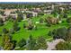 Aerial view showcasing the beautiful, lush green golf course, mature trees, and residential buildings in this community at 3274 S Heather Gardens Way, Aurora, CO 80014