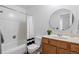 Renovated bathroom with tiled shower-tub, wood vanity, and round mirror at 3274 S Heather Gardens Way, Aurora, CO 80014