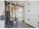 Functional basement with exposed pipes, hot water tank, and built-in white cabinets at 2633 Mather St, Brighton, CO 80601