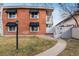 Charming brick exterior featuring black window awnings, manicured lawn, and pathway leading to the entrance at 160 Jackson St # 5, Denver, CO 80206